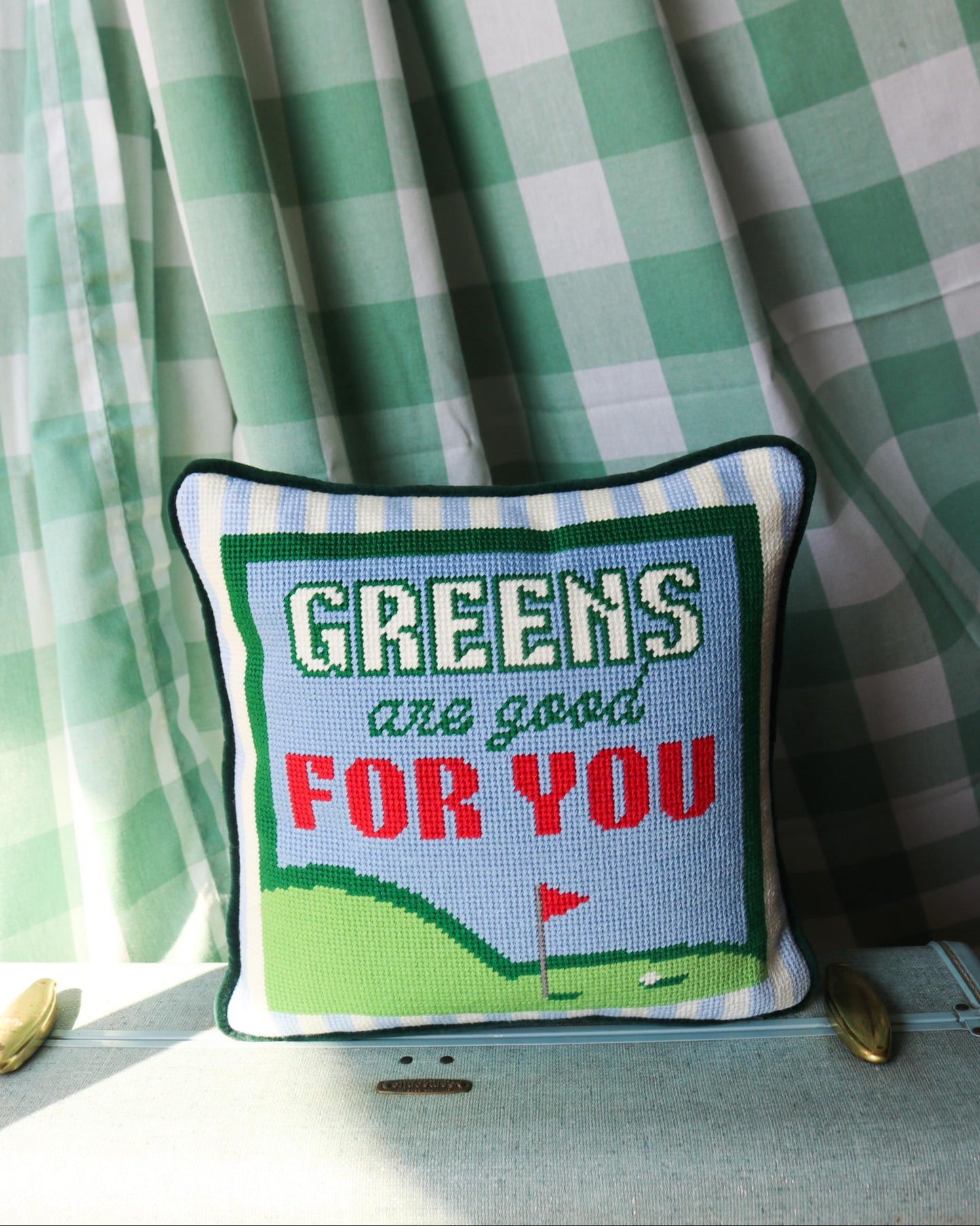 Decorative pillow with 'Greens are good FOR YOU' text against a green checkered curtain background
